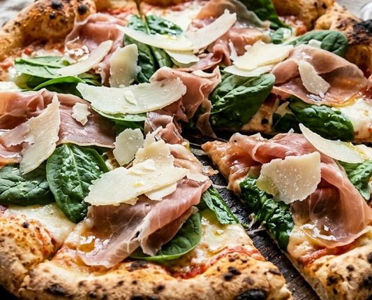 Close-up of a pizza with prosciutto, spinach, and cheese on a wooden board.