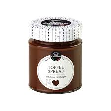Jar of toffee spread with a white lid on a white background