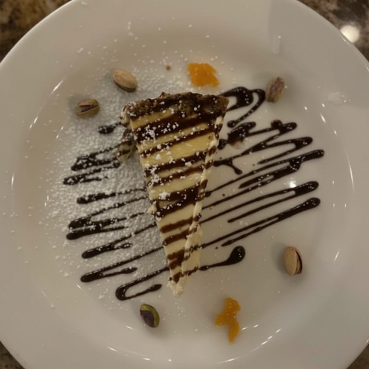 Slice of layered cake with chocolate drizzle on a white plate