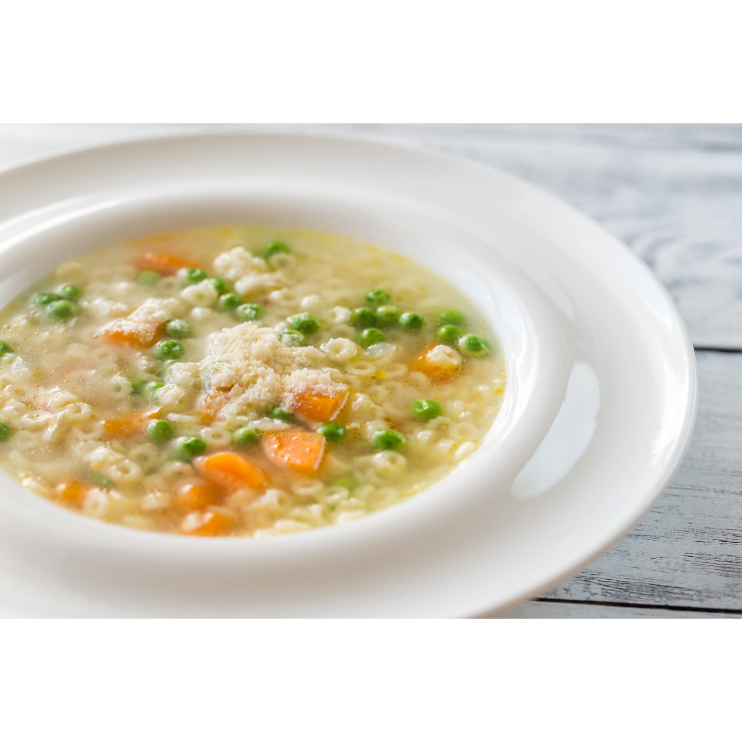 White bowl of creamy soup with vegetables on a wooden surface